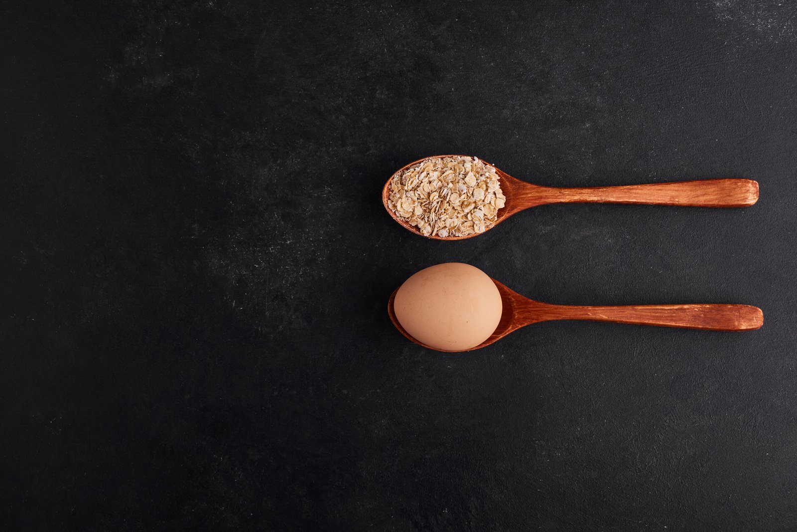 Egg and flour in wooden spoons in parallel style